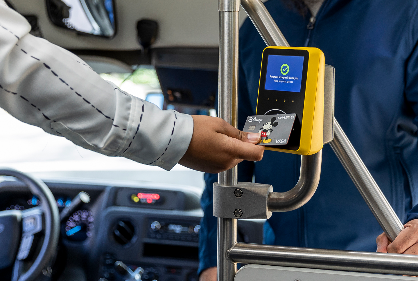 A passenger taps their contactless EMV card on a Kuba validator while boarding a bus
